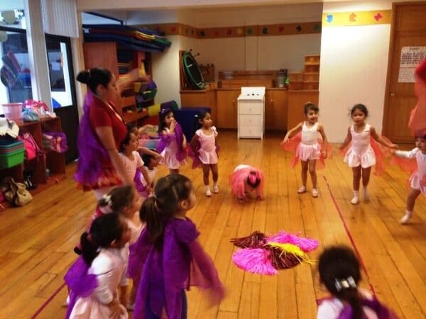 Alumnas con tutús rosas y morados desplazándose por el salón durante la clase de ballet