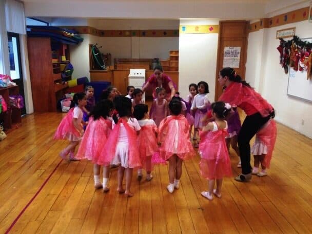 Alumnas con tutús forman un círculo cerrado junto a su maestra de ballet