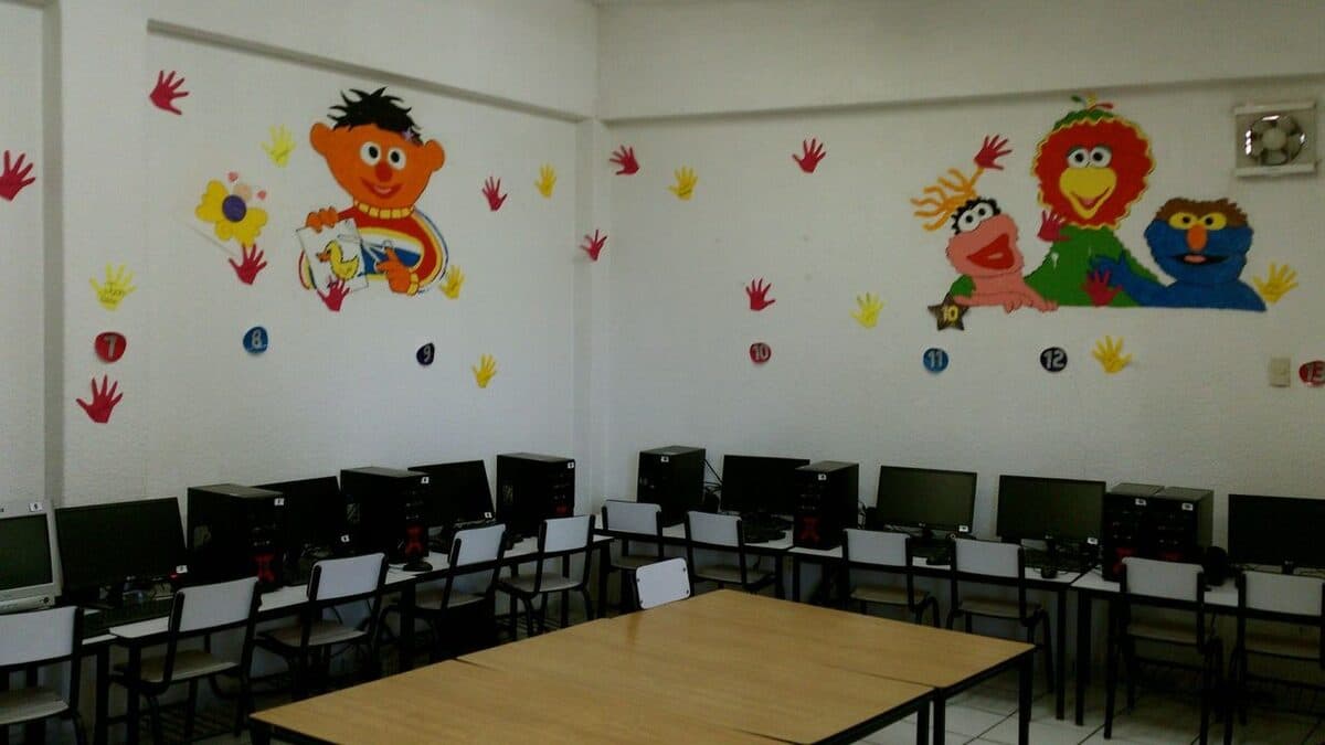 Aula de cómputo del colegio con los equipos alineados y murales de personajes en la pared