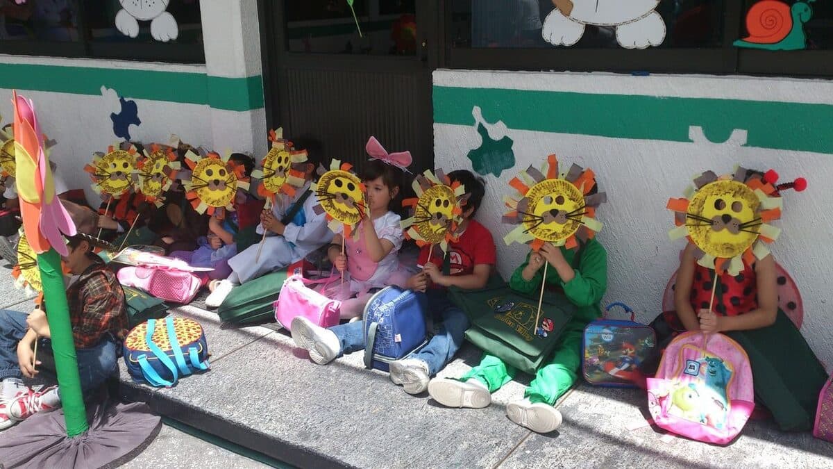 Alumnos sentados en el patio con las máscaras de león que ellos mismos elaboraron