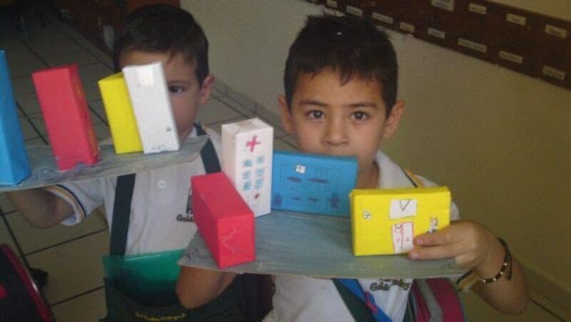 Alumno sostiene una bandeja con cajas de cartón que el grupo decoró para una actividad