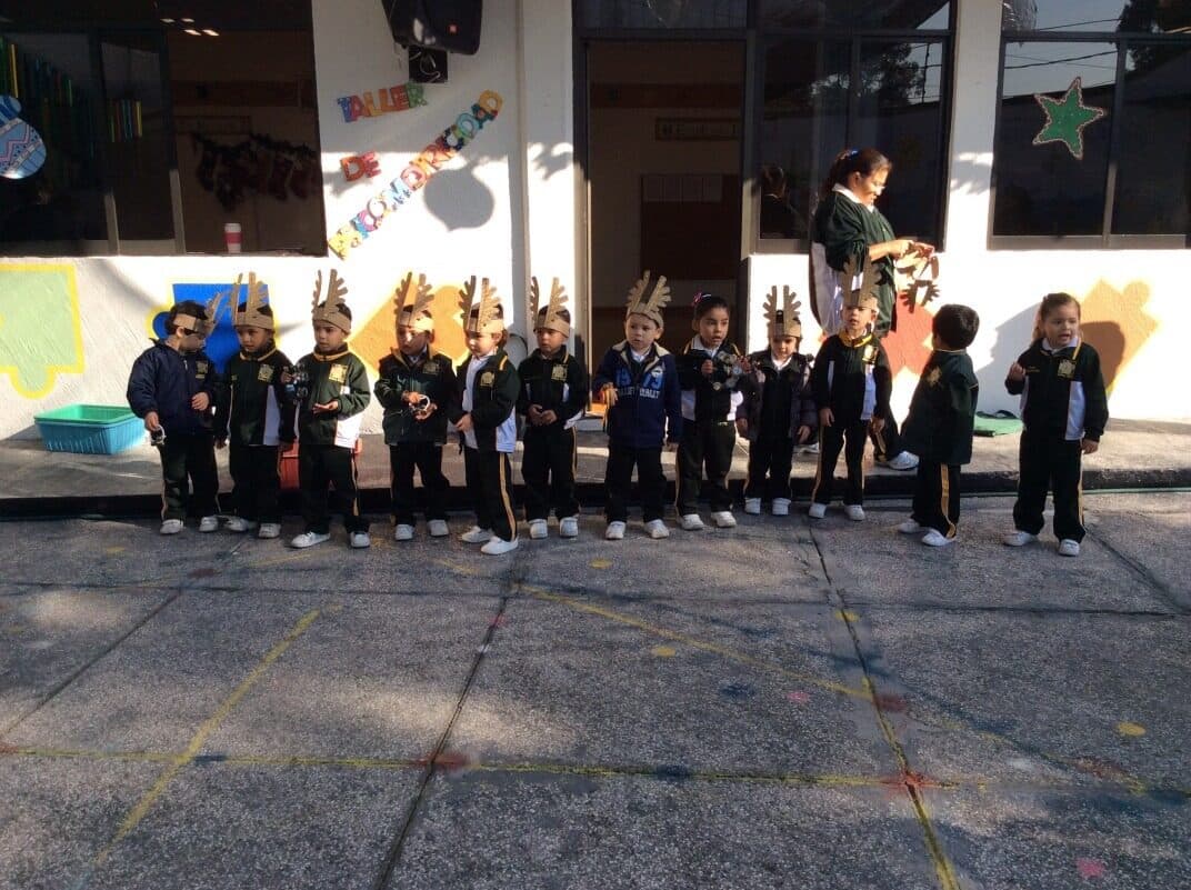 Alumnos formados en el patio con tocados de papel durante una presentación escolar