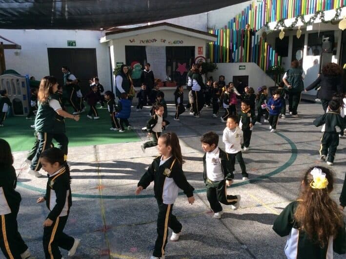 Alumnos en uniforme deportivo corriendo y jugando en el patio
