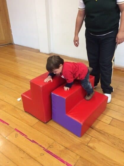 Niño pequeño se impulsa hacia la parte alta de la rampa de espuma roja