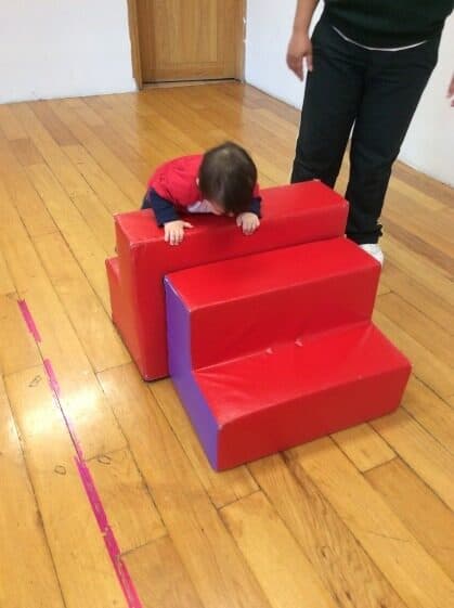 Niño pequeño termina de cruzar la rampa de espuma en el salón de psicomotricidad