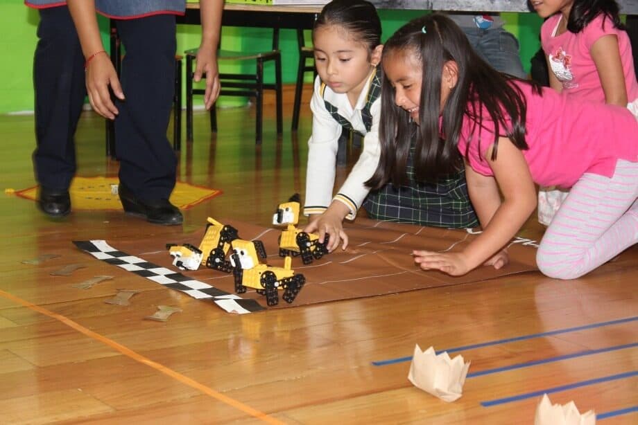 Dos alumnas guiando un carro robot sobre una pista marcada en el piso
