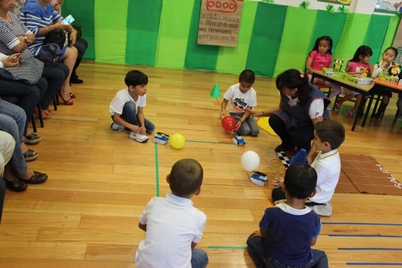 Alumnos lanzan sus robots por los carriles mientras el resto del grupo espera su turno
