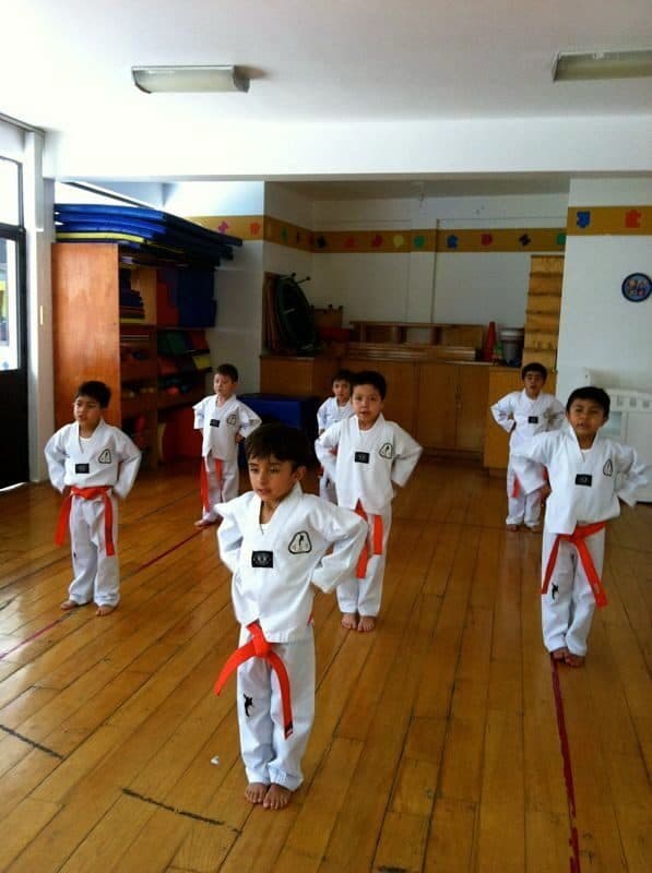 Dos alumnos con dobok blanco y cinta roja en posición de guardia durante la clase de Tae Kwon Do