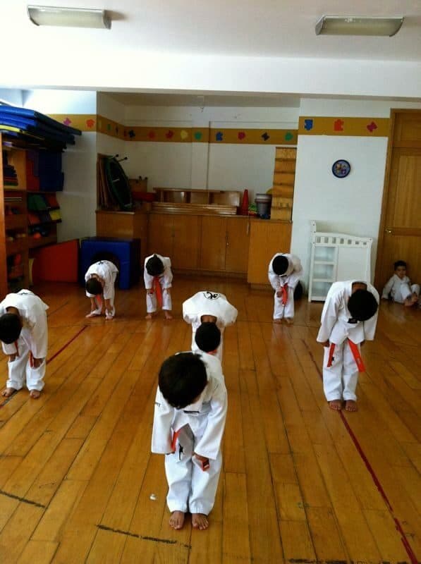 Alumnos con dobok hacen la reverencia de saludo durante la clase